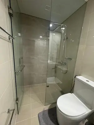 a bathroom with a toilet and a glass shower at JUANderful Home at Park McKinley West in Manila