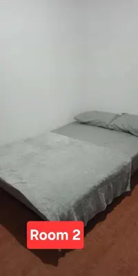 a bed with a room sign next to it at Auntie's in Tanza