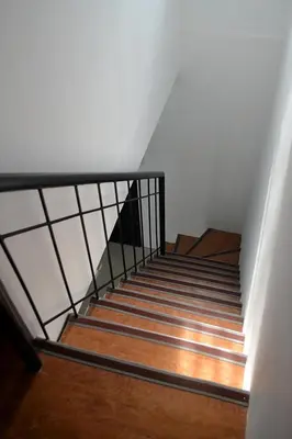 a staircase with a metal railing and wooden floors at Auntie's in Tanza