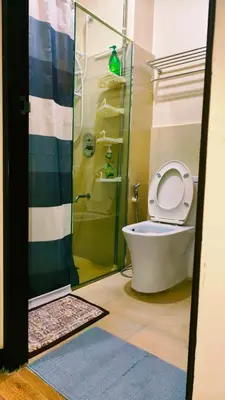 a bathroom with a toilet and a shower with the lid up at Cozy Corner at Paseo Verde with Free On-Site Private Parking in Manila