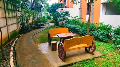 two wooden chairs and a table next to a building at Cozy Corner at Paseo Verde with Free On-Site Private Parking in Manila