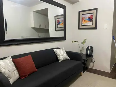 a black couch in a living room with a mirror at Sea Residences Tower F in Manila