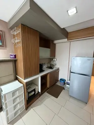 a kitchen with a white refrigerator and wooden cabinets at Antel Spa Residences 10E in Manila