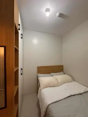 a small bedroom with a bed with white sheets at Eu & El Cozy Condo in Manila