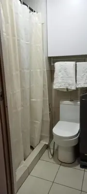 a bathroom with a toilet with a shower curtain at Eu & El Cozy Condo in Manila