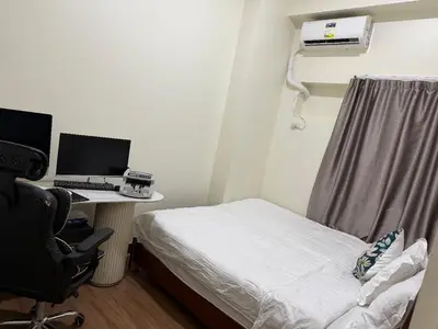 a room with a bed and a desk with a computer at fairlane residences in Manila