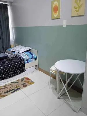 a small bedroom with a bed and a table at Modern Comfort in Pasay with Pool in Manila