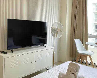 a living room with a television on a white dresser at City View Condo in Pasig with Pool, WiFi and Netflix in Manila