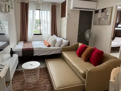 a living room with a couch and a bed at Dainty Den LS217- Chic & Relaxing Stay Near Enchanted Kingdom in Santa Rosa