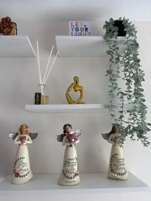 three figurines of angels sitting on a shelf next to a shelf with a plant at Dainty Den LS217- Chic & Relaxing Stay Near Enchanted Kingdom in Santa Rosa