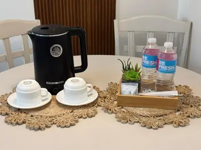 a table with a tea kettle and cups and bottles of water at Dainty Den LS217- Chic & Relaxing Stay Near Enchanted Kingdom in Santa Rosa