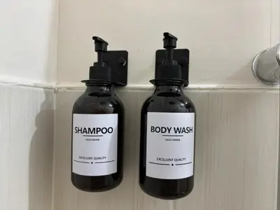 two bottles of shampoo and body wash on a wall at Dainty Den LS217- Chic & Relaxing Stay Near Enchanted Kingdom in Santa Rosa