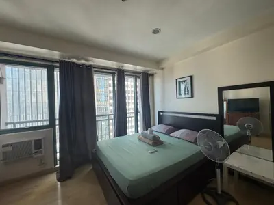 a bedroom with a bed with a fan and windows at SOHO Central Condotel in Manila