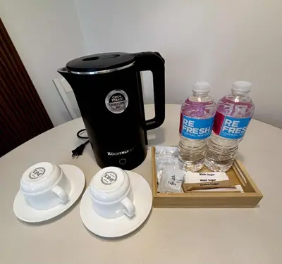a coffee maker and two cups and water bottles on a table at Dainty Den Renovation in Macabling