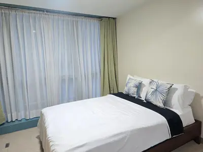 a bedroom with a large white bed with a window at Modern BGC One Uptown 1BR near Grand Hyatt Uptown Mitsukoshi Malls and St Lukes Medical Center in Manila