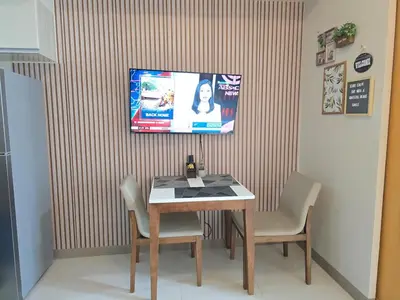a table and chairs with a television on a wall at Modern BGC One Uptown 1BR near Grand Hyatt Uptown Mitsukoshi Malls and St Lukes Medical Center in Manila
