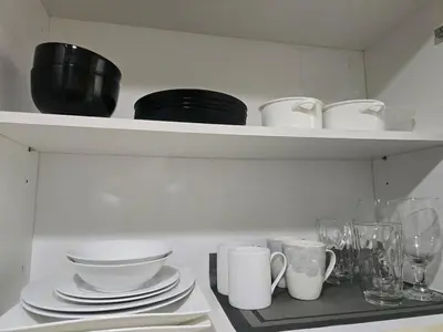 a shelf with plates and cups and dishes on it at Modern BGC One Uptown 1BR near Grand Hyatt Uptown Mitsukoshi Malls and St Lukes Medical Center in Manila