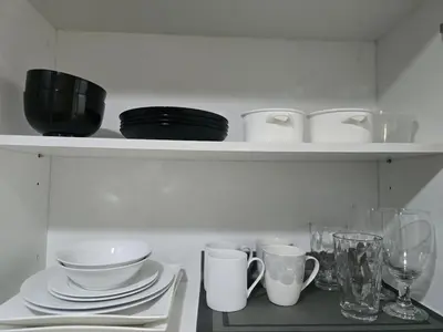 a shelf with plates and cups and glasses on it at Modern BGC One Uptown 1BR near Grand Hyatt Uptown Mitsukoshi Malls and St Lukes Medical Center in Manila