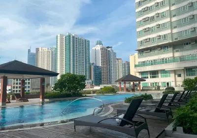 a swimming pool with chairs and umbrellas in a city at City View Unit near Makati CBD in Manila