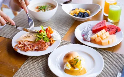 a table with plates of breakfast food on it at Belmont Hotel Manila near NAIA Terminal 3 MNL in Manila
