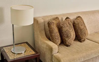 a couch with pillows on it with a lamp on a table at Belmont Hotel Manila near NAIA Terminal 3 MNL in Manila
