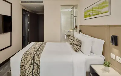 a bedroom with a large white bed and a sink at Belmont Hotel Manila near NAIA Terminal 3 MNL in Manila