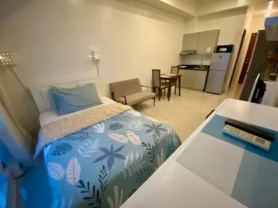 a small bedroom with a bed and a kitchen at Affordable Nordic Style Condo in Makati in Manila