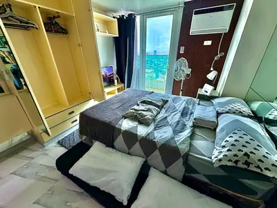 a bedroom with a large bed with a large window at Cozy Condo at MakatiCBD in Manila