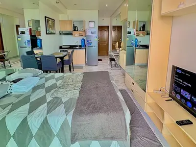 a room with a large bed with a tv and a kitchen at Cozy Condo at MakatiCBD in Manila