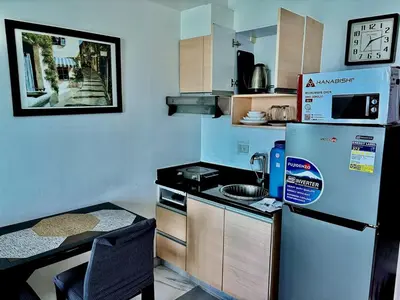 a small kitchen with a refrigerator and a table at Cozy Condo at MakatiCBD in Manila