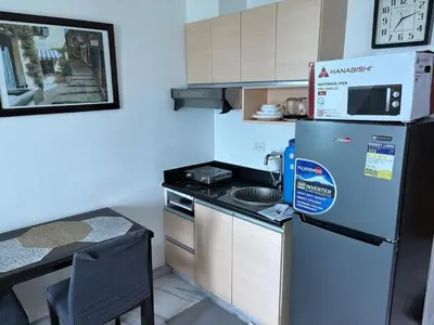 a small kitchen with a refrigerator and a table at Cozy Condo at MakatiCBD in Manila