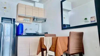 a kitchen with a table with two chairs and a refrigerator at High End Penthouse Makati CBD in Manila
