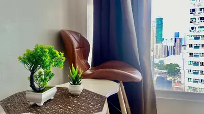 a brown leather chair sitting next to a table with plants at High End Penthouse Makati CBD in Manila