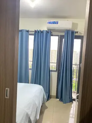 a bedroom with blue curtains and a bed and a window at Shore 2 tower 2 in Manila