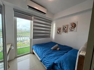 a bedroom with a blue bed and a large window at Shore Residences in Manila