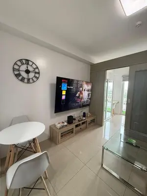 a living room with a table and a clock on the wall at Shore Residences in Manila