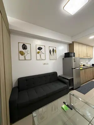 a living room with a black couch and a kitchen at Shore Residences in Manila