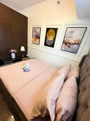 a bed in a bedroom with pictures on the wall at City Comfort Staycation 1BR Air Residences Makati in Manila
