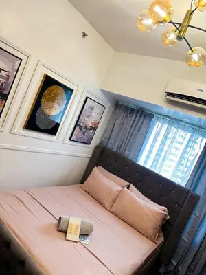 a bed in a room with pictures on the wall at City Comfort Staycation 1BR Air Residences Makati in Manila