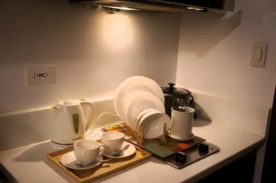 a kitchen counter with plates and cups on a tray at City Comfort Staycation 1BR Air Residences Makati in Manila