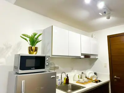a kitchen with a microwave on top of a refrigerator at City Comfort Staycation 1BR Air Residences Makati in Manila