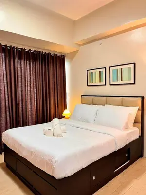 a bedroom with a large bed with white sheets at Big Studio Unit in Newport near NAIA w Balcony in Manila