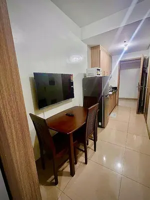a kitchen with a table and chairs and a television at Manial Mall of Asia 1 Bedroom Shore 2 Residence in Manila