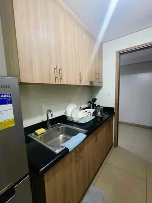 a kitchen with a sink and wooden cabinets at Manial Mall of Asia 1 Bedroom Shore 2 Residence in Manila