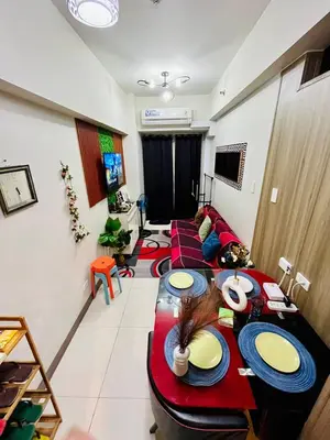 a living room with two long tables in a room at Staycation ni Gelo in Manila