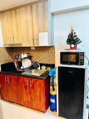 a kitchen with a sink and a microwave and a christmas tree at Staycation ni Gelo in Manila