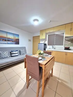 a living room with a table and a kitchen at Stayscape at Kensington in Manila