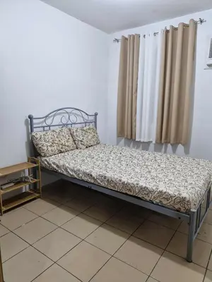 a bed sitting in a room next to a window at Stayscape at Kensington in Manila