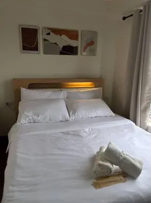 a white bed with two towels on top of it at The Camden Place in Manila