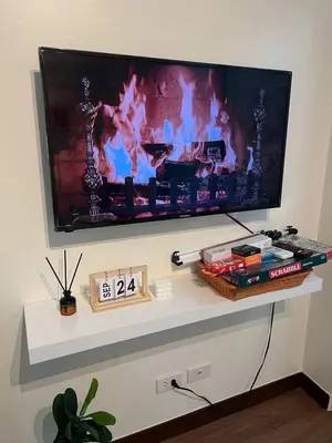 a flat screen tv on a wall with a fireplace at The Camden Place in Manila